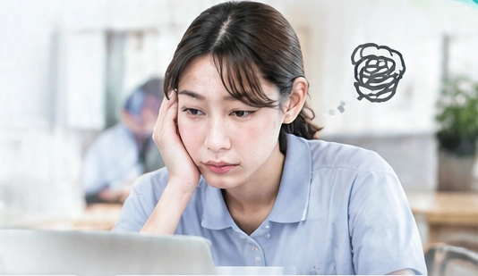 パソコンの前で業務について悩む職員